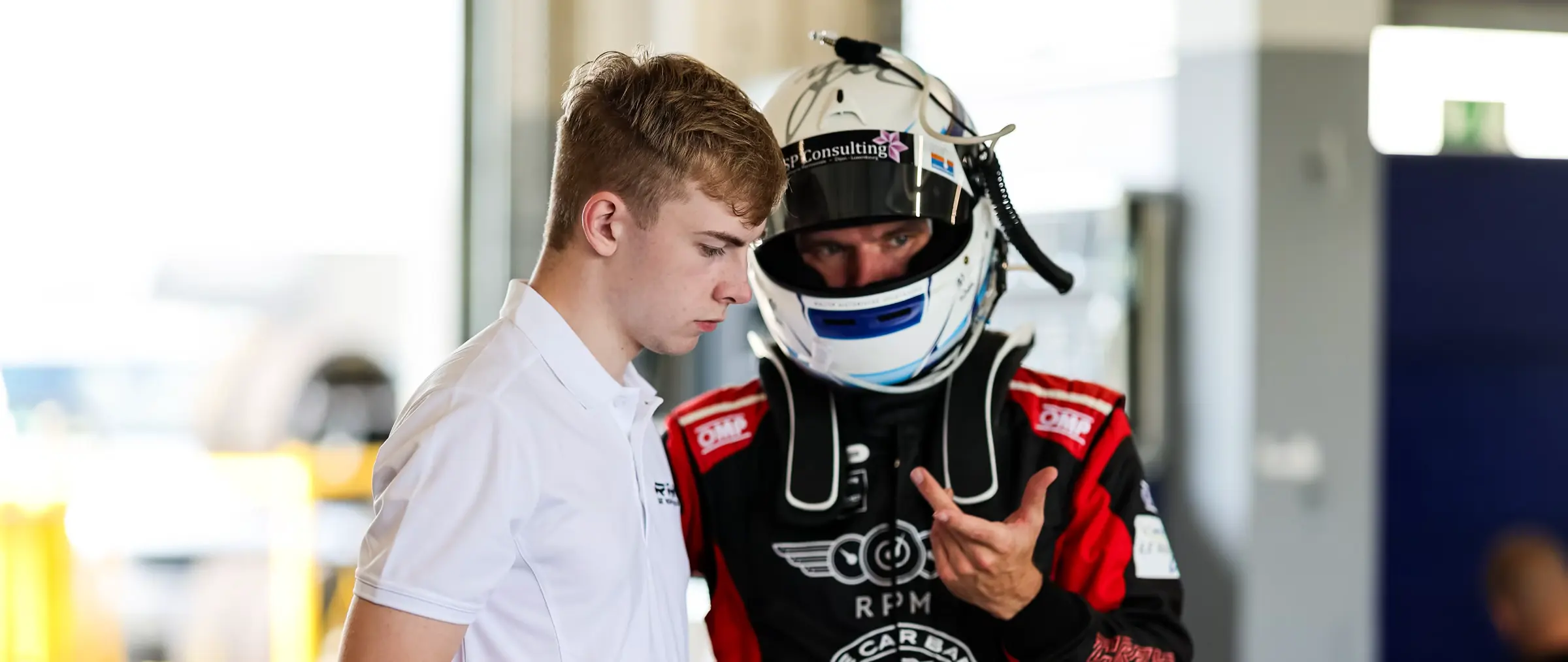 Trackside conversation between an engineer and a driver in helmet and race suit